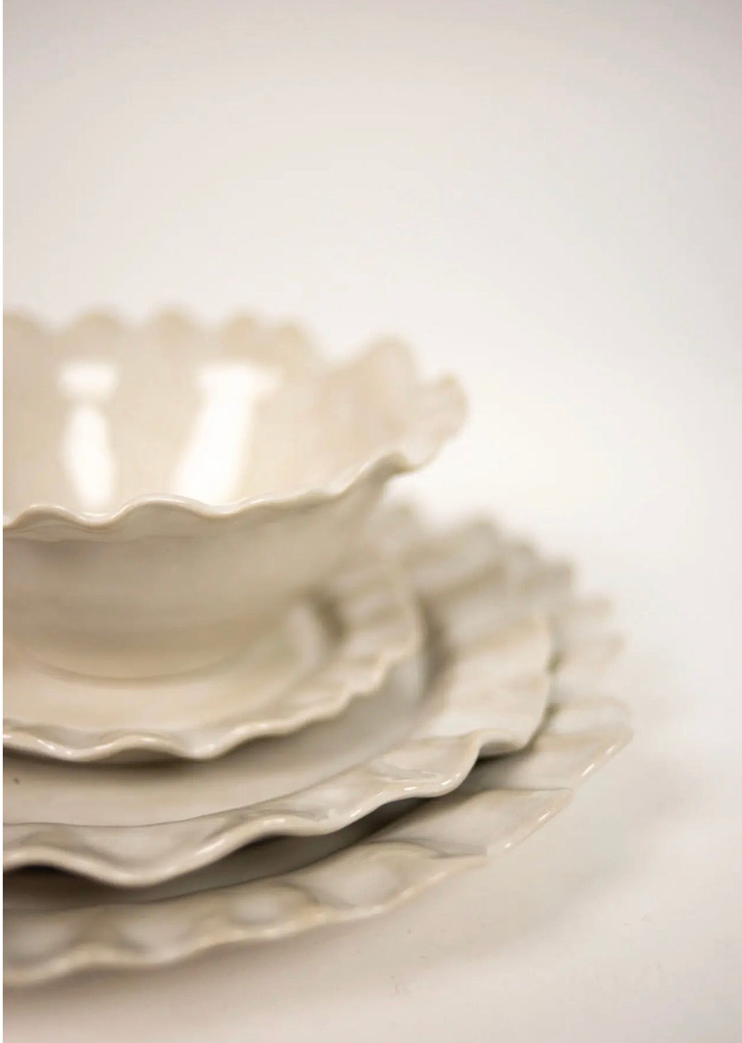 Valerie series — stacked white stoneware bowl and plates with wavy edges, editorial close-up