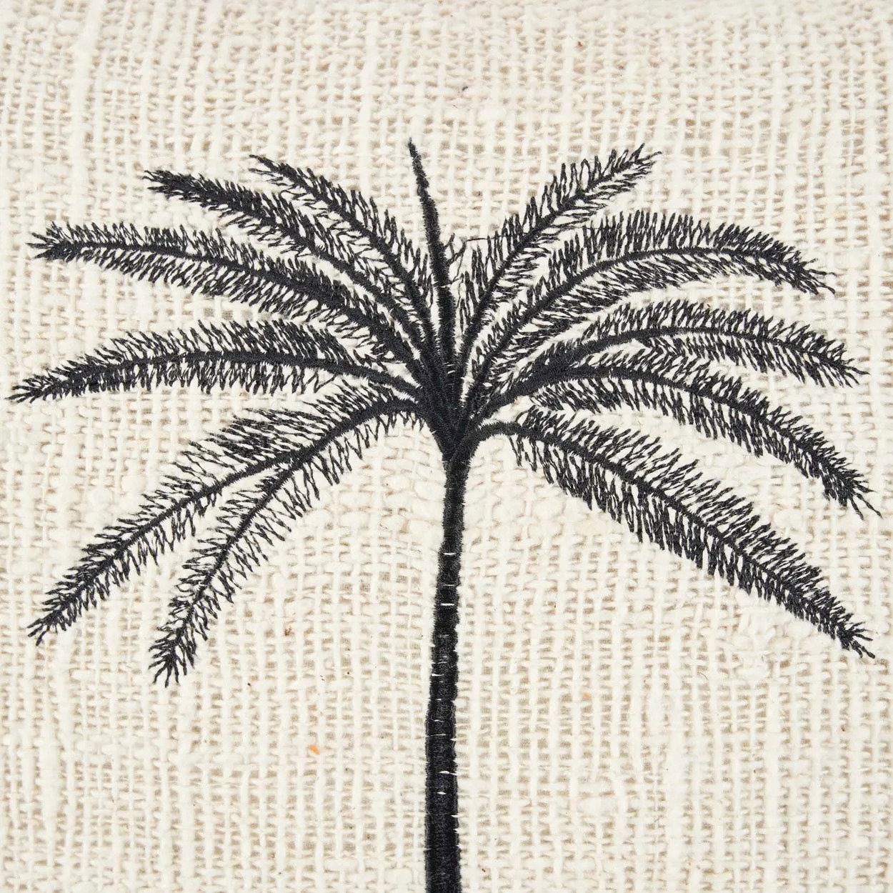 The Gili Palm Cushion Cover — lifestyle shot on striped sofa with second cushion
