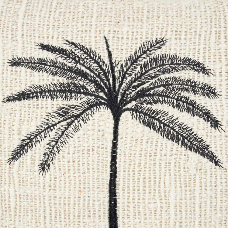 The Gili Palm Cushion Cover — lifestyle shot on striped sofa with second cushion