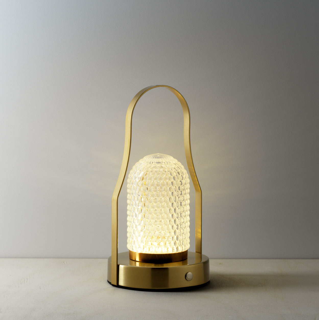 The Lampuccino LED Table Lamp, lit on grey surface