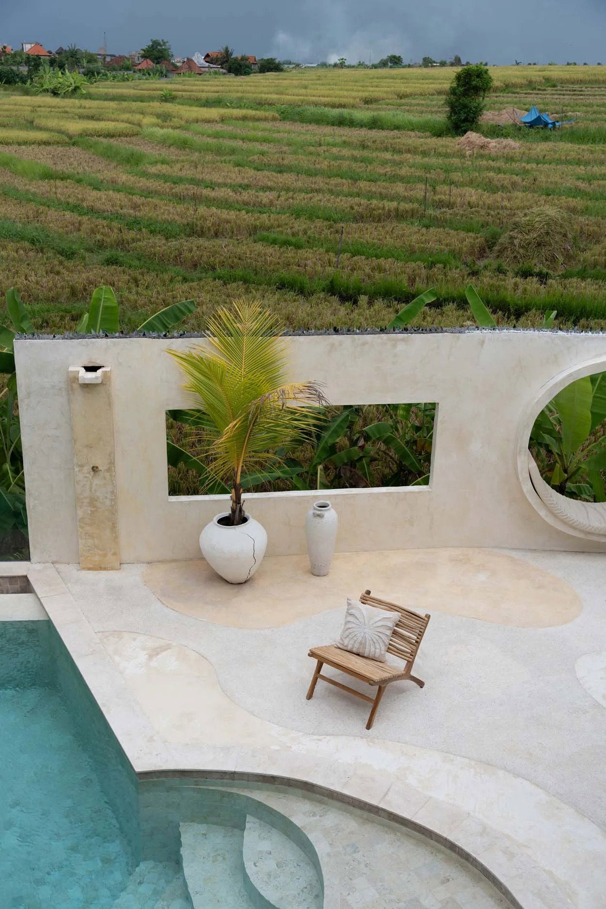 The Isla Palm Cushion Cover — lifestyle shot on daybed with striped cushion and rattan accent