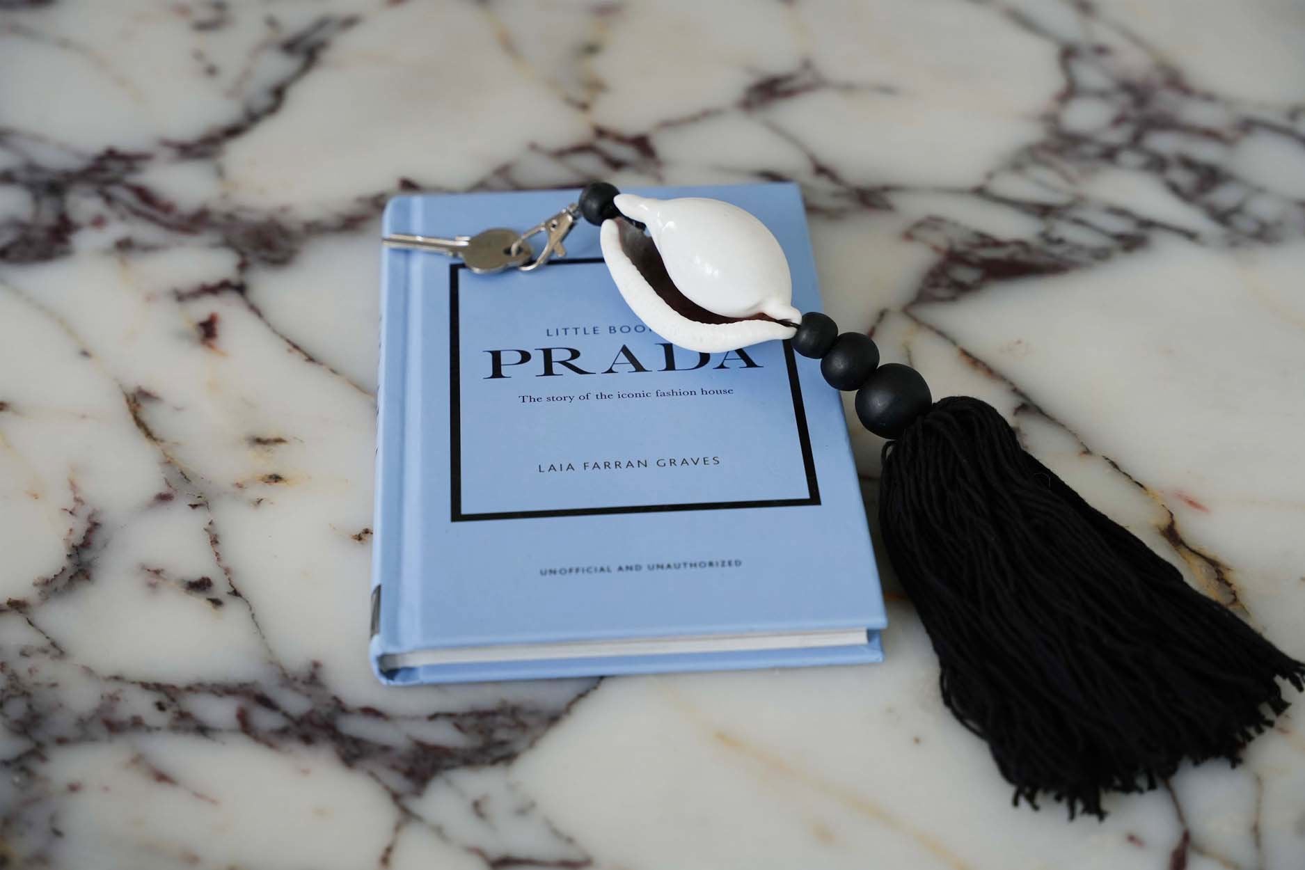 The Togian Keychain — Black White, lifestyle on marble with green juice and coaster