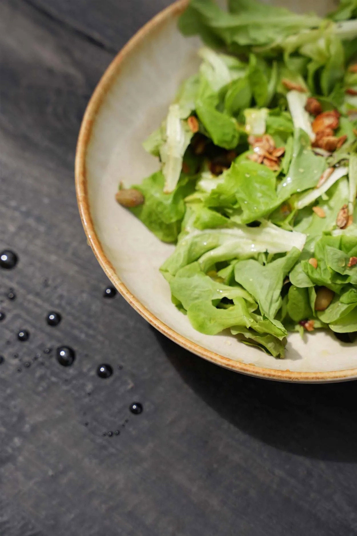 The Cascais Small Bowl Plate styled with a salad and golden fork on a dark slate surface