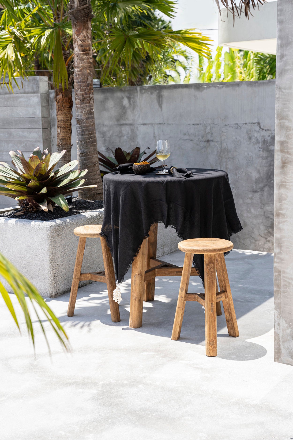 The Linen Tablecloth — Black 150×200, lifestyle flat lay with lemons and book