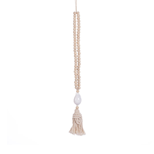 The Ocean Whisper Necklace — detail of white cowrie shell and macramé tassel, editorial lifestyle shot