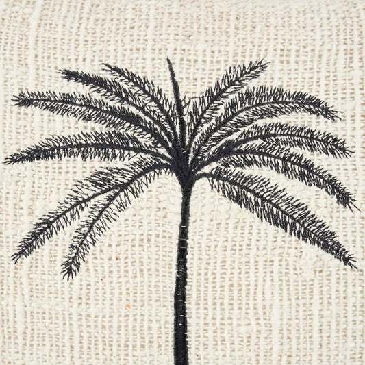 The Gili Palm Cushion Cover — lifestyle shot on striped sofa with second cushion