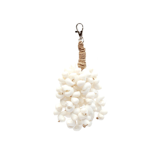 The Kai Shell Keychain — White, lifestyle hanging on aged wooden door with ivy