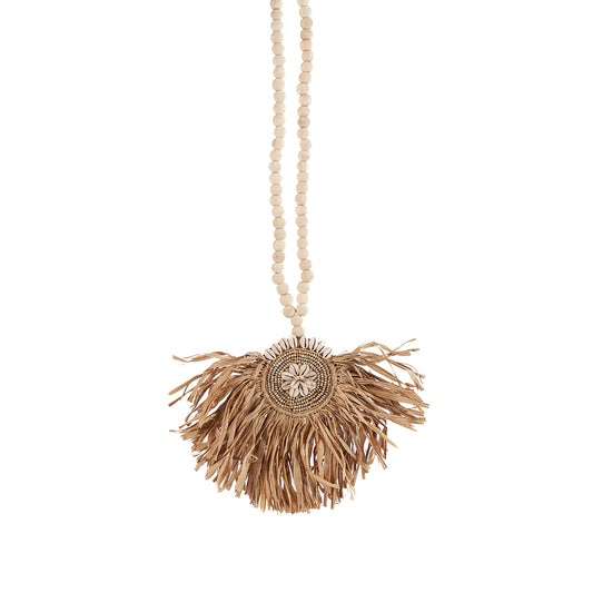 The Raffia Tajoe Tassel — Natural, lifestyle hanging on arched wall beside wooden door