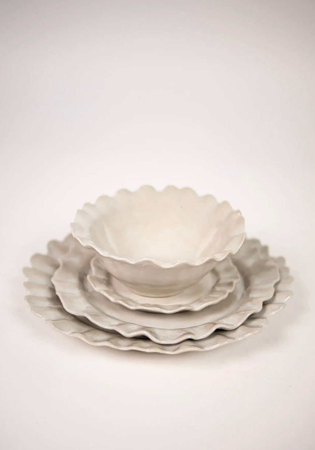 Valerie series — stacked white stoneware plates and bowl with wavy edges on white background