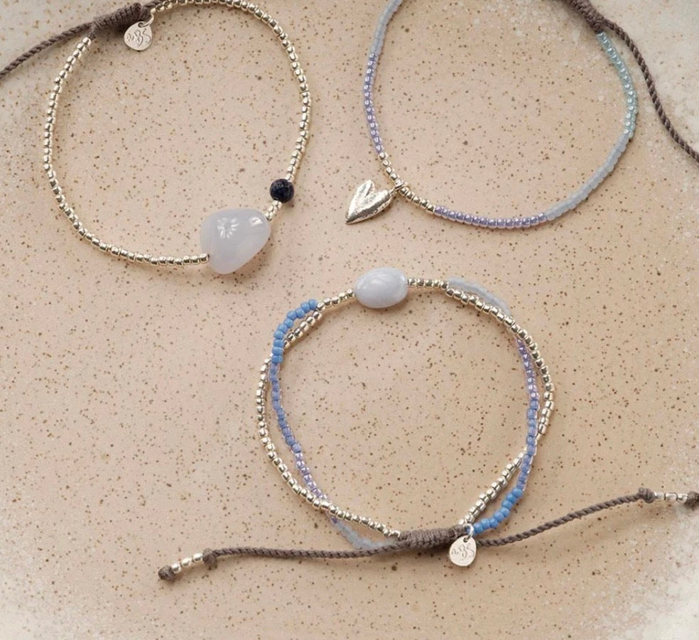 Surprise Blue Lace Agate Bracelet – Styled flat lay on sand with other bracelets